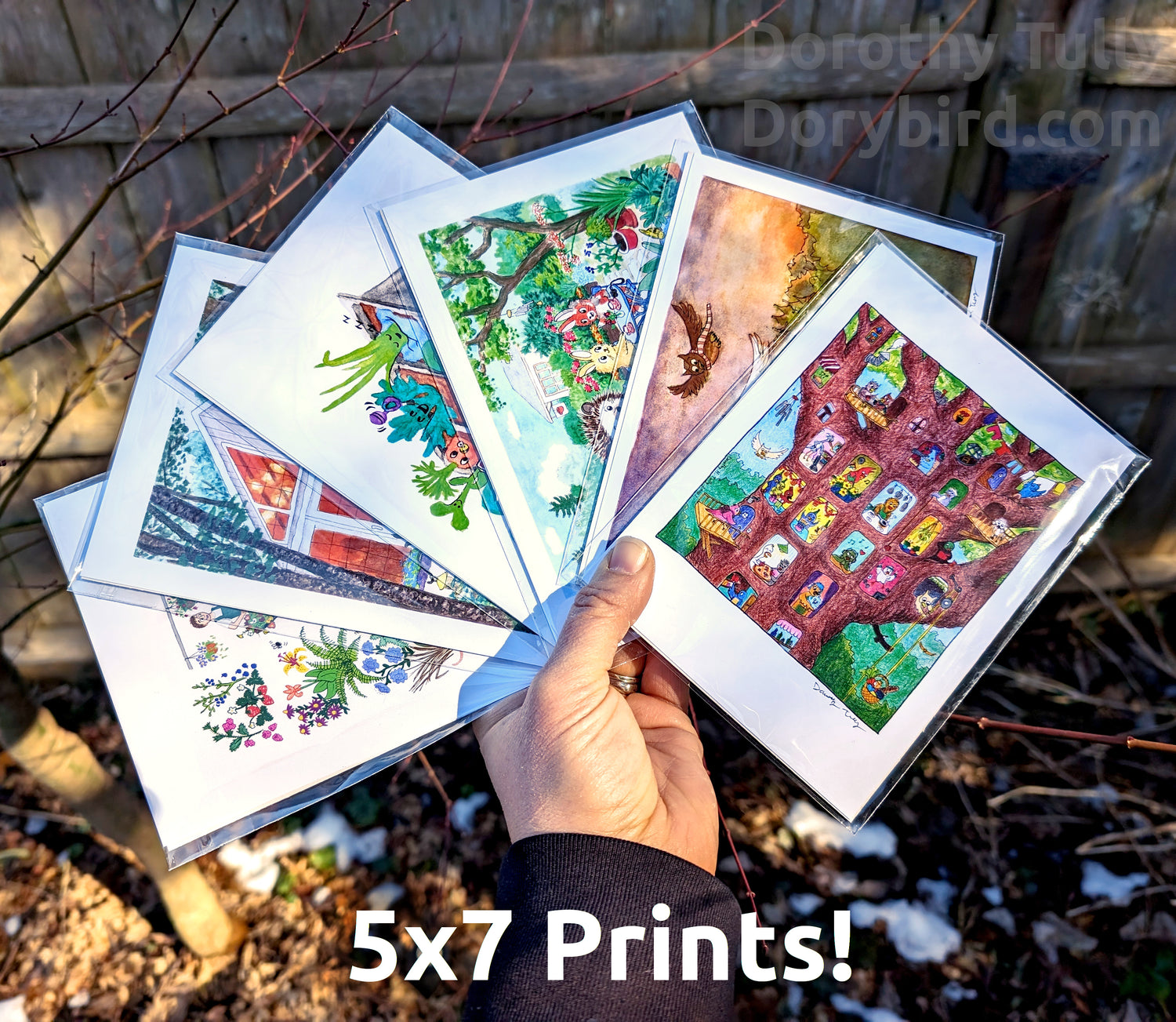 a hand holding 6 of artist Dorothy Tully's 5x7 small art prints of animals, plants, childrens illustrations