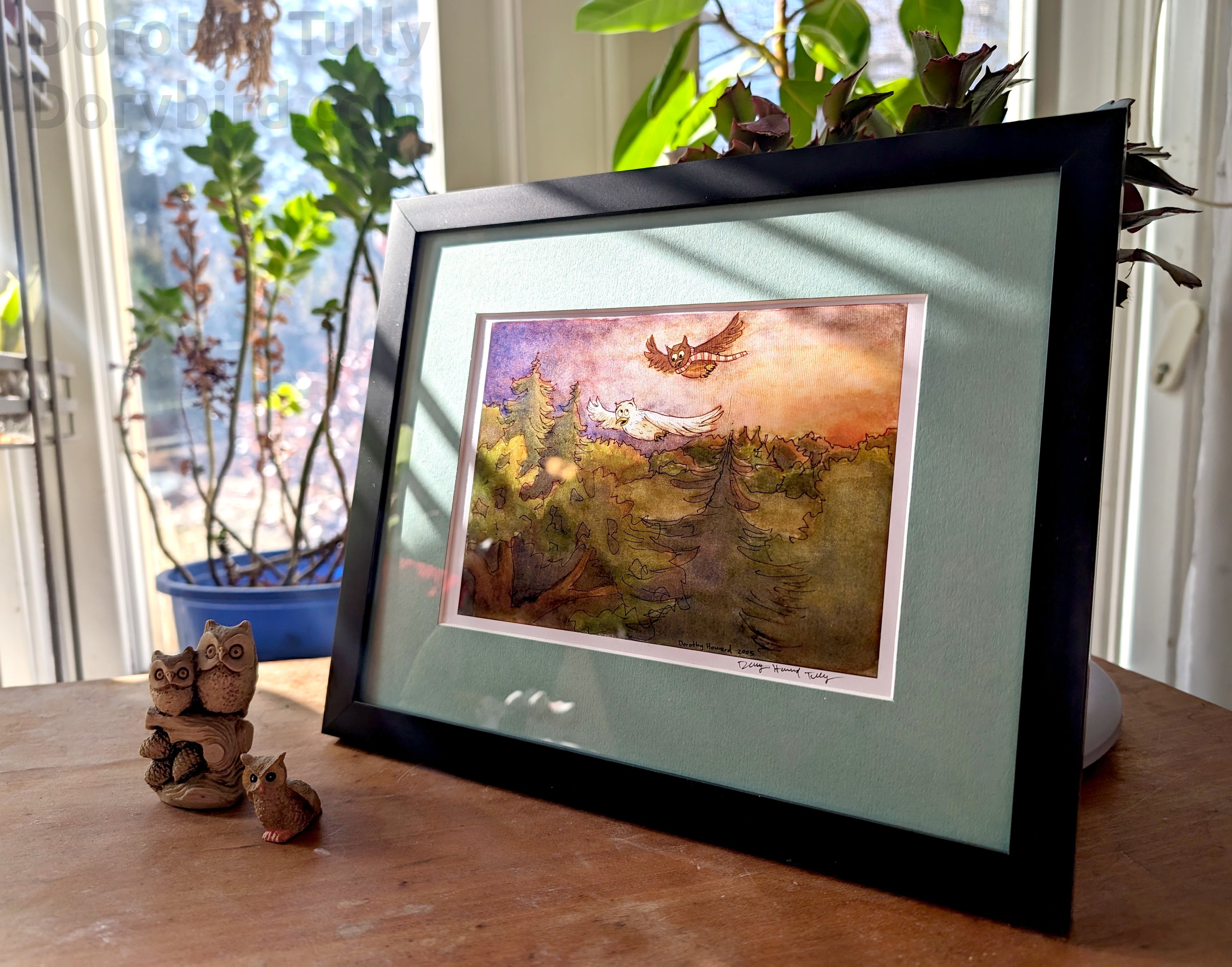 A framed print of Dorothy Tully's Flight Owls watercolor illustration, cartoon owls flying over a forest at sunset