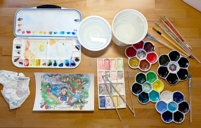 A rainbow of watercolor paints, Japanese pigment inks, brushes, and an illustration in progress on artist Dorothy Tully's desk